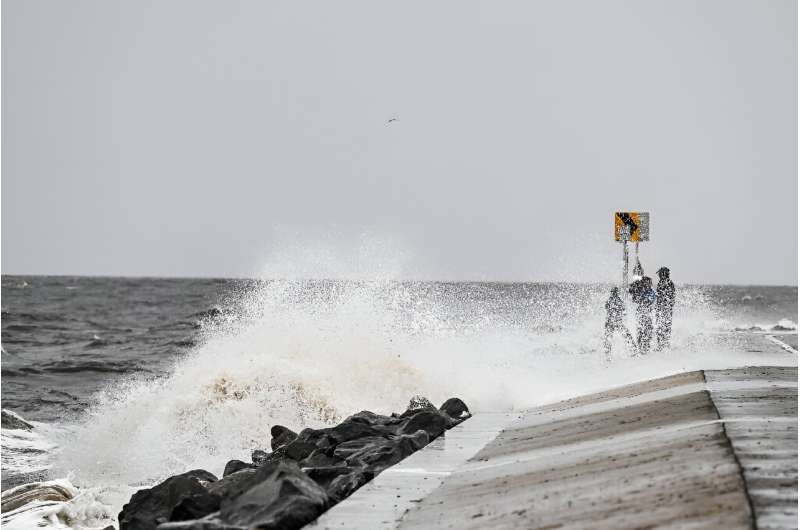 People stand on the shoreline ahead of the arrival of Hurricane Helene in Alligator Point, Florida