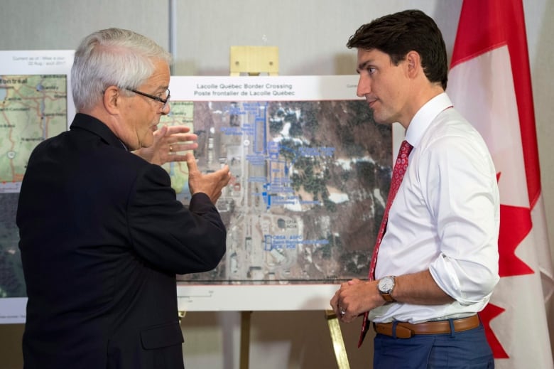 Trudeau and a man with grey hair look at a map