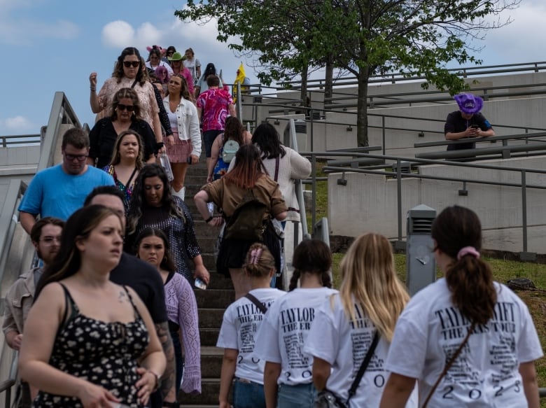 Several people, mostly female, are shown outdoors walking in opposite directions.