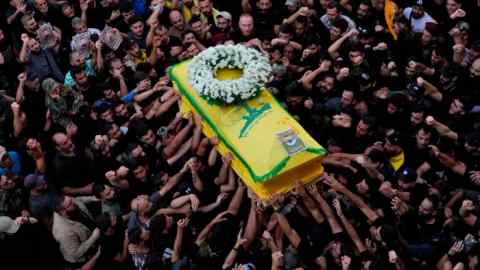 Hezbollah members carry the coffin of their comrade who was killed on Wednesday when a handheld device exploded, during a funeral procession in the southern suburbs of Beirut