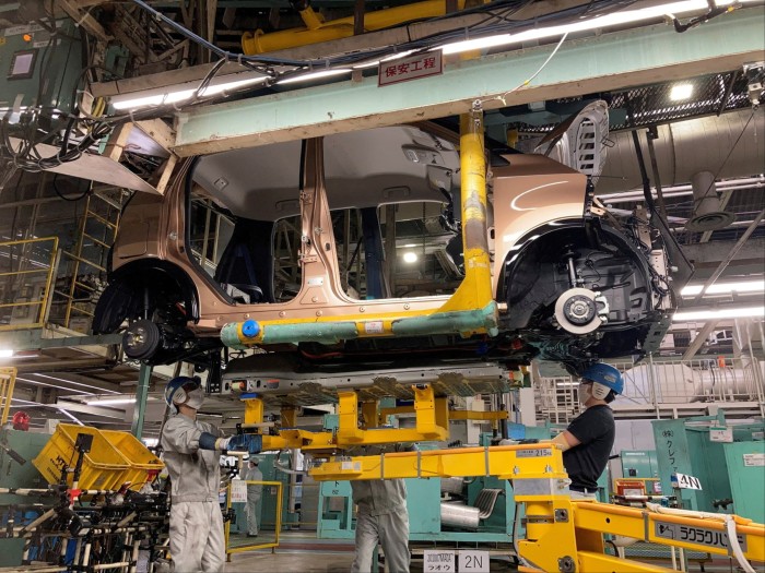 Workers install a battery in an electric vehicle at Mitsubishi Motor’s factory in Kurashiki, Japan