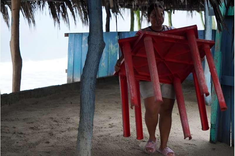 A woman brings tables in from the beach in southern Mexico ahead of the arrival of Hurricane John