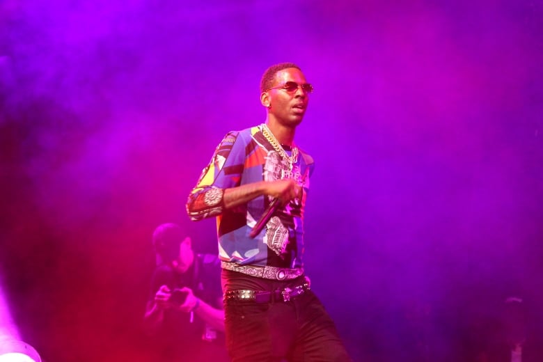 Young Dolph performing in moody purple lighting.