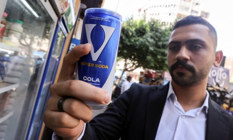 A man holds up a can of soda. 