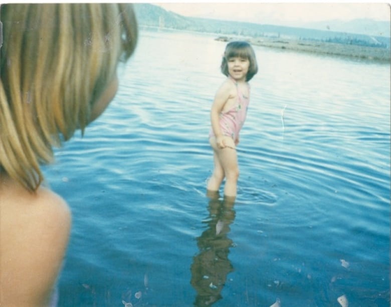 An old photo of a little girl standing in a lake. 