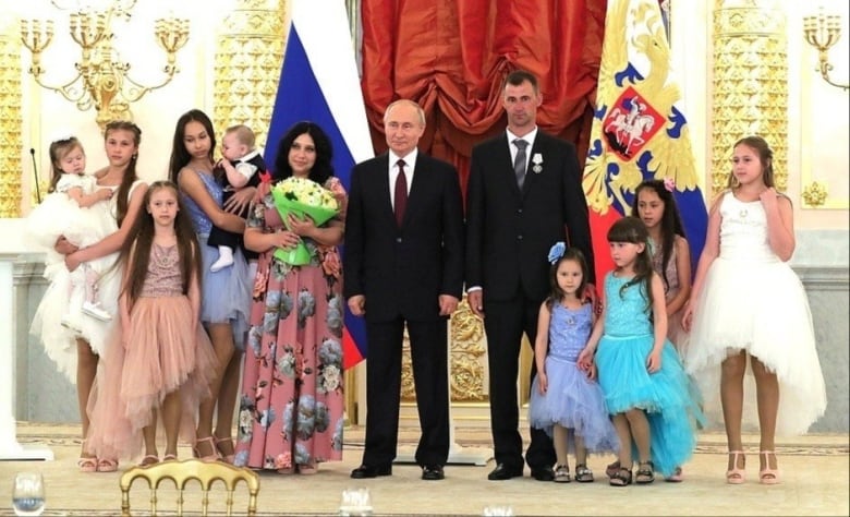 Lilia Syropyatova stands with her husband and their 9 children alongside Russian President Vladimir Putin, who awarded them with the Russian honour of "Parental Glory." "