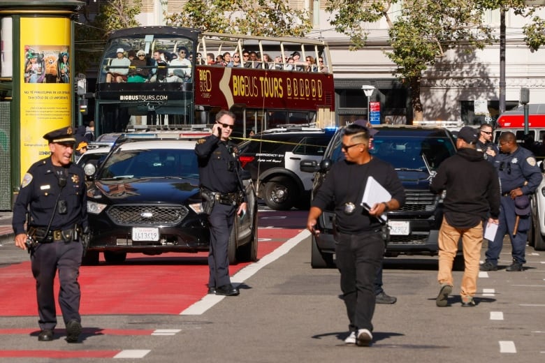 Six police officers are shown on the street in front of several vehicles.