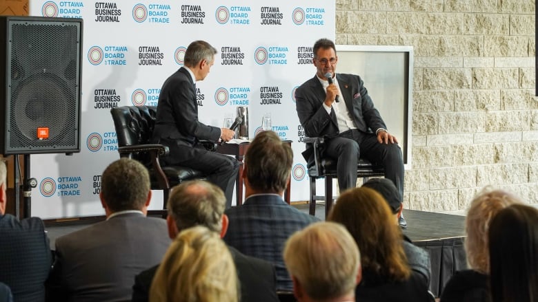 A mayor talks to a sports team owner at a corporate breakfast event.