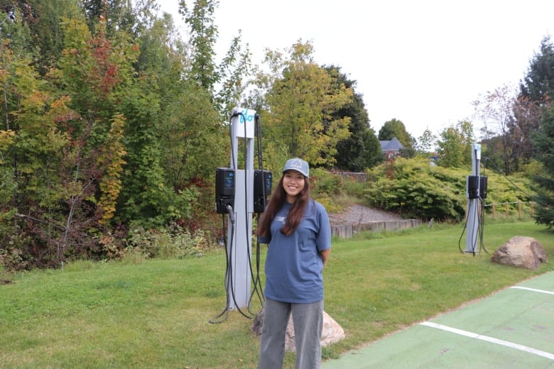 A woman stands in an electric vehicle parking space