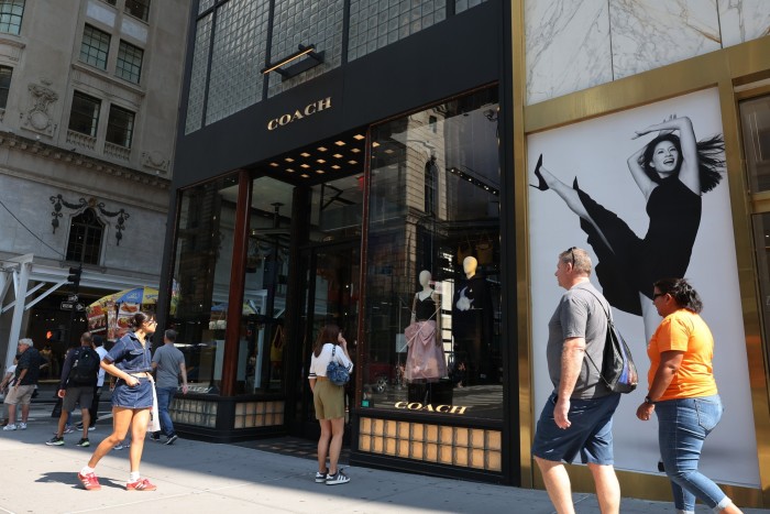 People walk past a store for Coach, which is owned by Tapestry