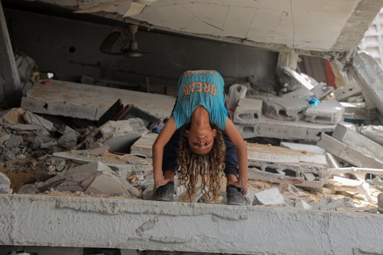 A boy does a bridge on top of a collapsed building.