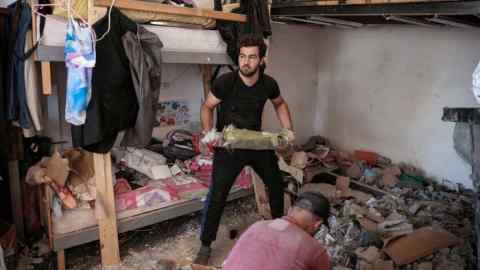 People clean debris from a damaged house amid ongoing search for survivors, a day after an Israeli strike on residential buildings in Maaysrah, north of Beirut, Lebanon.