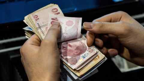 A cashier counts 5 and 10 Turkish lira banknotes in Istanbul, Turkey