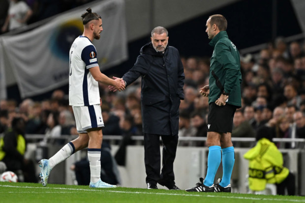 Radu Dragusin of Tottenham Hotspur shakes hands with Ange Postecoglou.