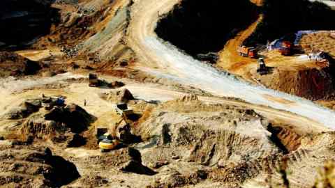 Aerial view of an excavator loading trucks with rare earth at a mine