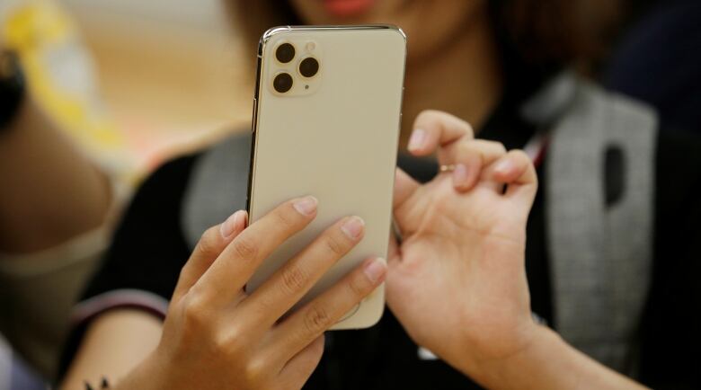 A woman holds a phone in one hand and scrolls with the other. 