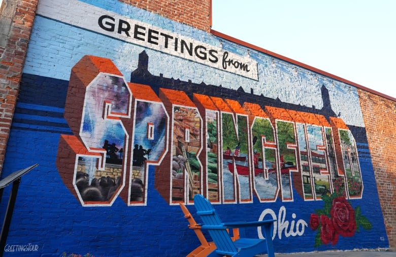 A mural shows the message "Welcome to Springfield Ohio" on the side of a brick wall.