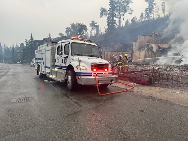 Firefighters are pictured spraying structure during wildfires that entered Jasper, Alta.