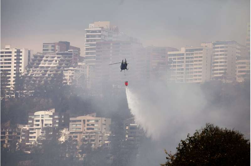 A helicopter sprays water over a bushfire on a hill in Quito on September 25, 2024