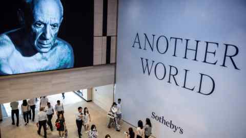 People walking beneath a large image of a man and the words ‘Another World’ at the centre