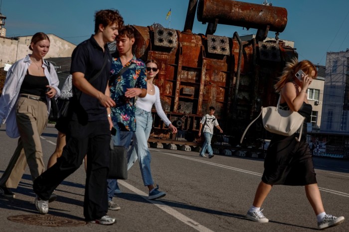 Locals pass an installation with a power transformer damaged by a Russian strike in Kyiv