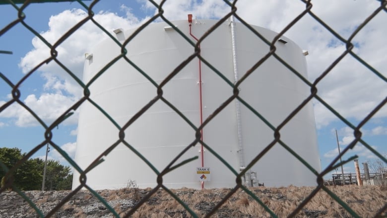 a large white holding tank behind a chainlink fence