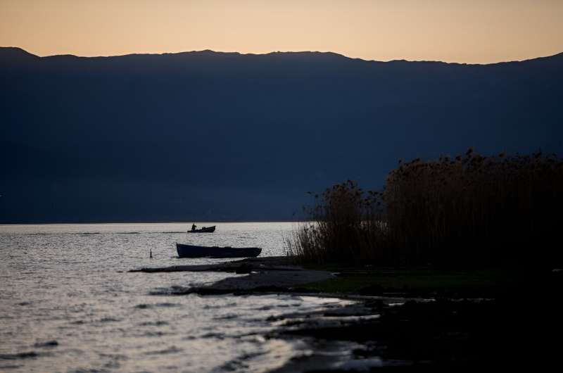 A fishing boat plies the waters of Great Prespa Lake, which are also receding