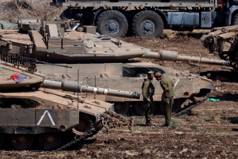 Israeli members of the military stand next to armoured vehicles, amid cross-border hostilities between Hezbollah and Israel, in northern Israel, September 30, 2024. 