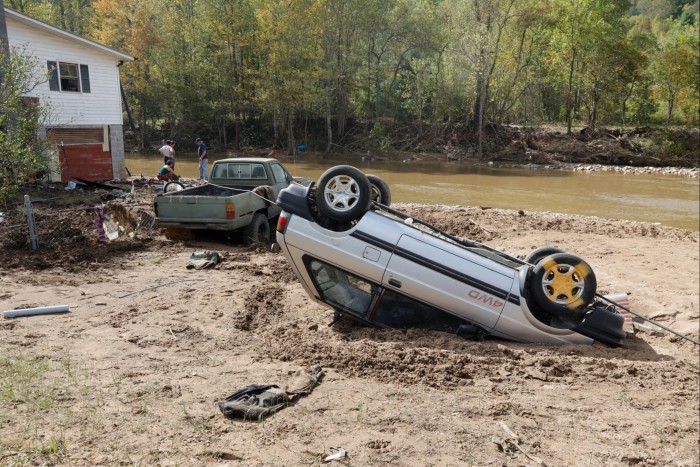 Overturned car lies in mud near a flooded creek in Barnardsville, North Carolina