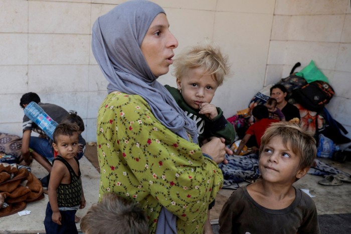 Displaced from Dahiyeh, southern Beirut suburb, Asmaa Kenji holds one of her three children as they live on the streets of central Beirut after fleeing the Israeli air strikes, in Beirut, Lebanon