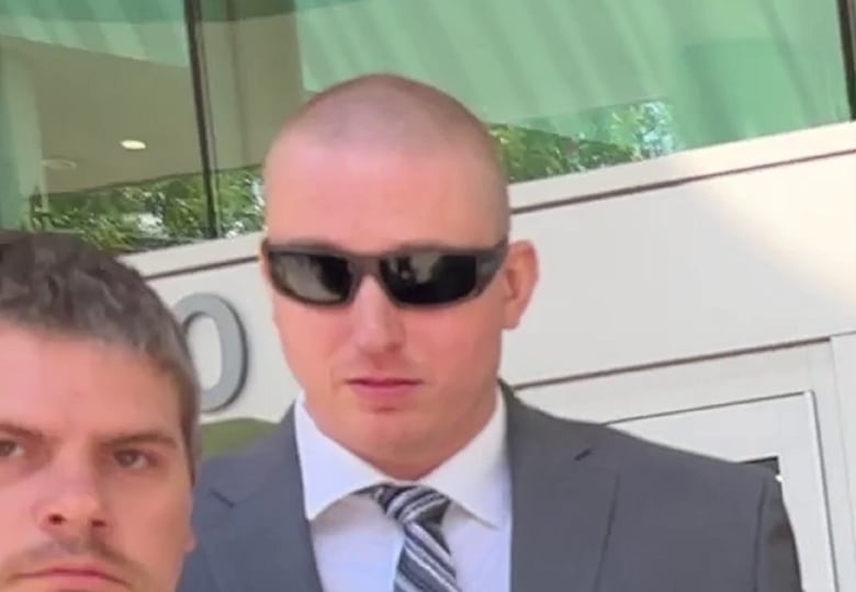 A man in a suit wearing sunglasses leaves a court building.