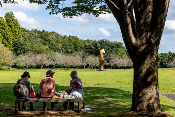 Women resting on a bench with a view towards Henry Moore’s sculpture in the distance 