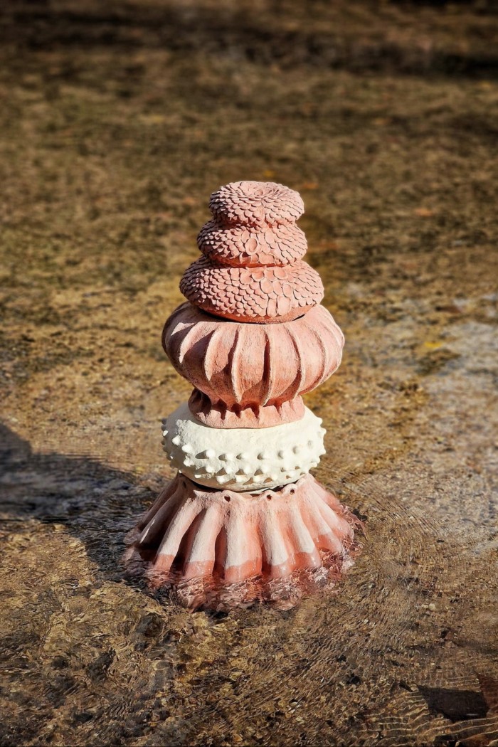 A pink ceramic object featuring a series of overlapping, highly patterned cupolas on top of each other 