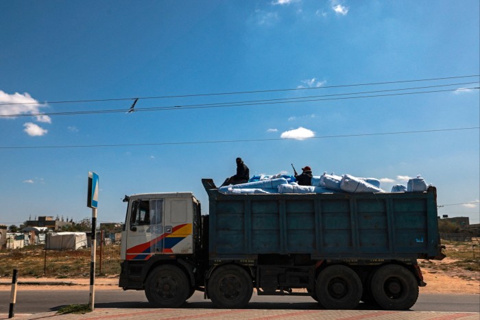 Masked members of the ‘Popular Committees of Protection’ sit on top of a truck carrying humanitarian aid in Rafah