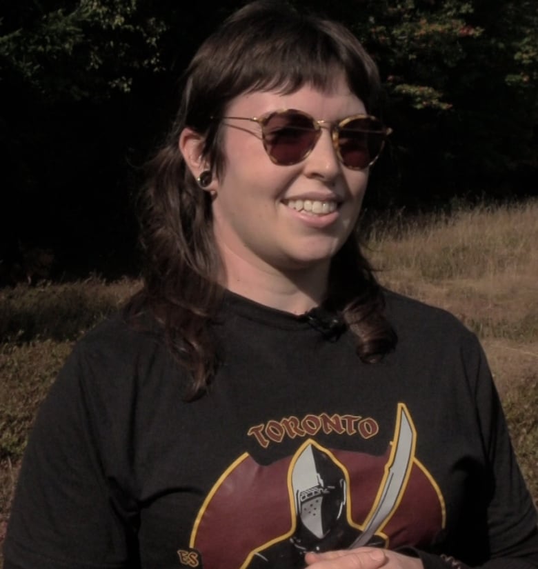 a mid shot of a woman standing wearing sunglasses