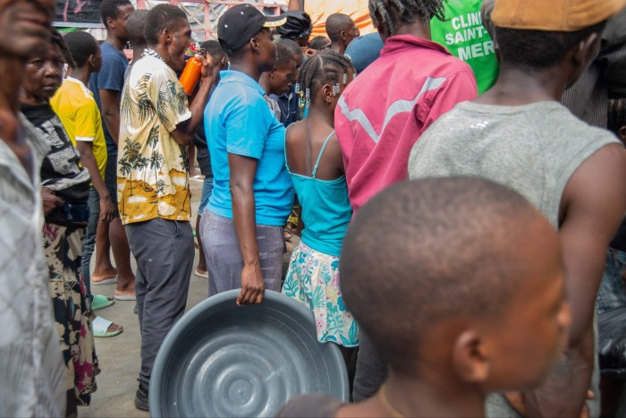 People wait for a food distribution in a displaced persons camp at the Lycée Marie Jeanne school in Port-au-Prince on October 2