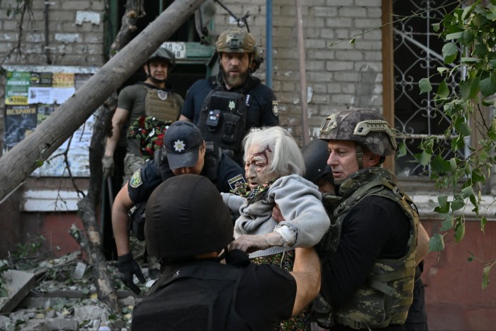 Ukrainian police officers help a wounded woman escape a building hit by a Russian strike in the Donetsk region