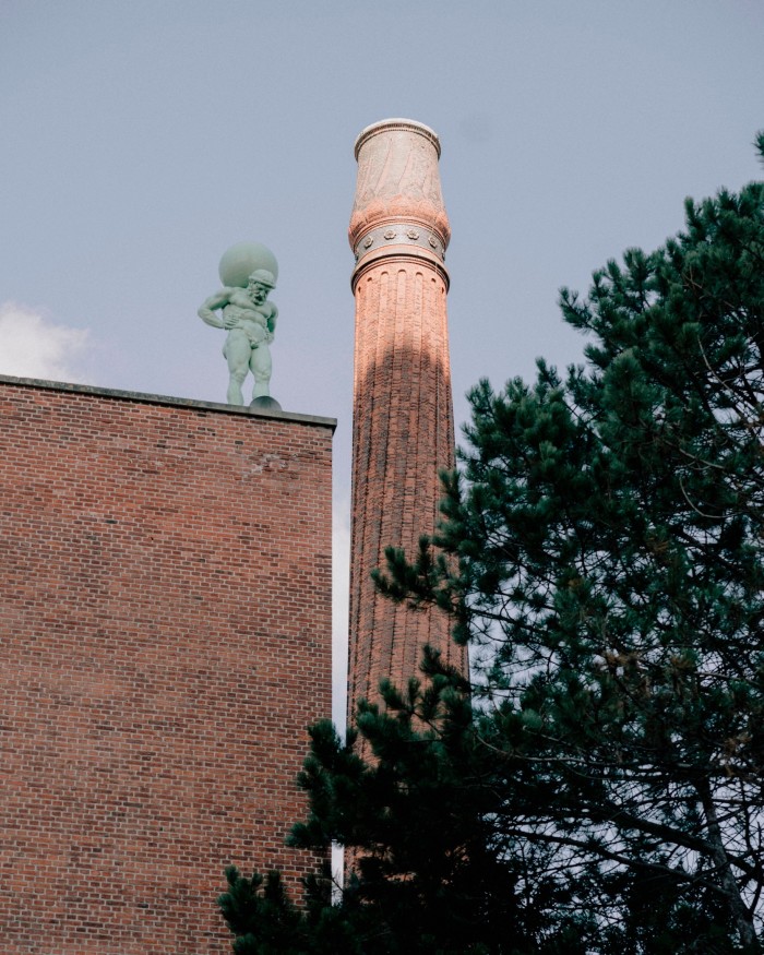 Carlsberg’s pink-hued, 56-metre Winding Chimney, with a statue of Atlas standing on a roof below it