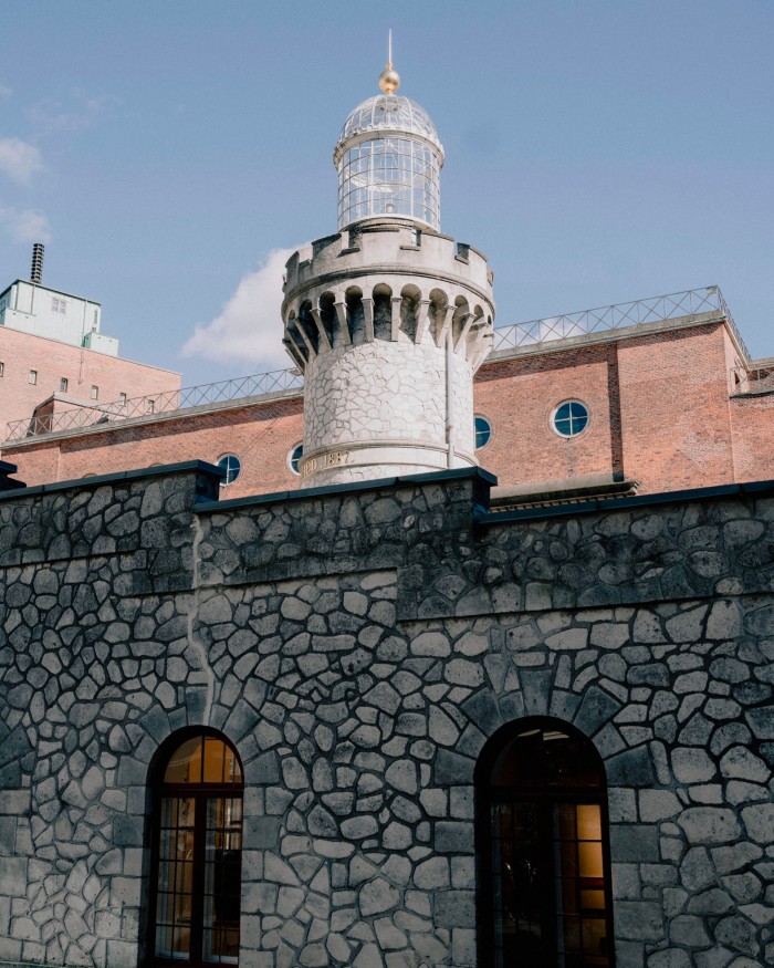 The top half of the Chalk Tower, a late-19th-century lighthouse, in front of which is a dark-grey wall made of irregular-shaped stones