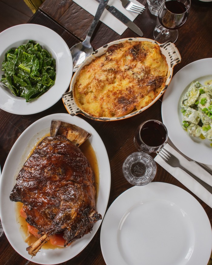 A shoulder of lamb and side orders of greens and a gratin dish on a table at the Canton Arms