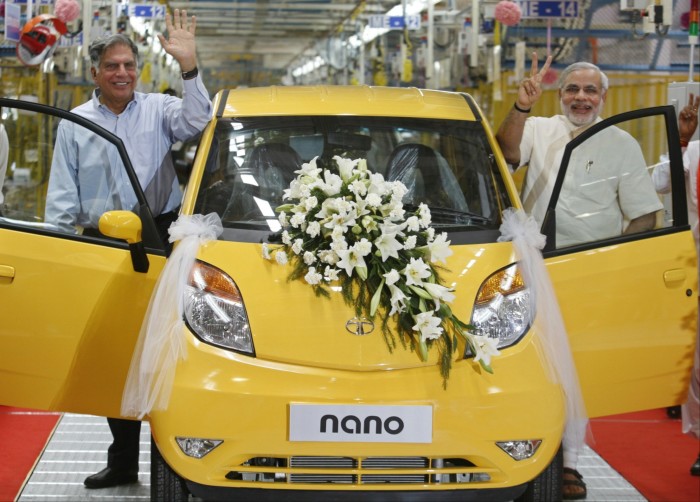 The two men pose with a bright yellow nano bedecked with flowers