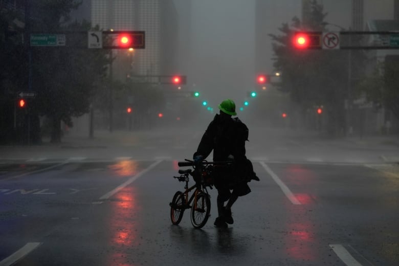 Ron Rook, who said he was looking for people in need of help or debris to clear, walks through windy and rainy conditions on a deserted street in downtown Tampa, Fla., during the approach of Hurricane Milton on Wednesday.