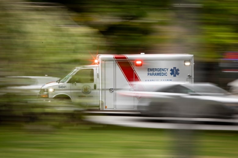 An ambulance rushes by with flashing red sirens.