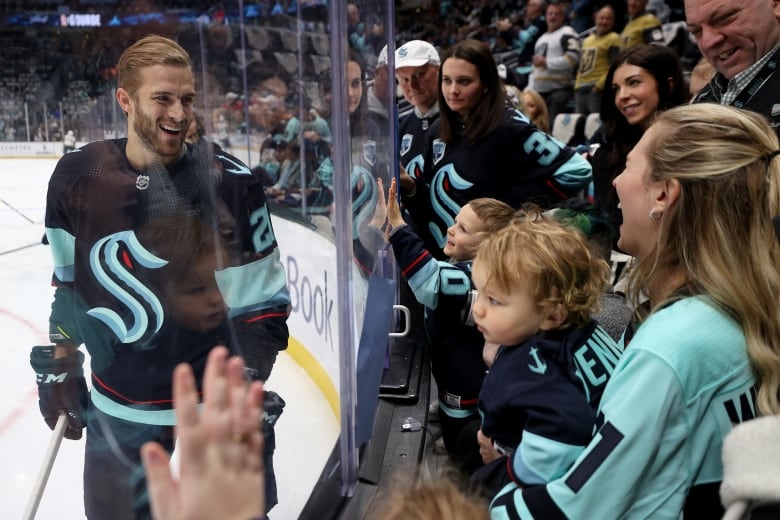 SEATTLE, WASHINGTON - APRIL 13: Alex Wennberg #21 of the Seattle Kraken greets his family Felicia and Rio through the glass during warmups before the game against the Vegas Golden Knights at Climate Pledge Arena on April 13, 2023 in Seattle, Washington. (Photo by Steph Chambers/Getty Images)