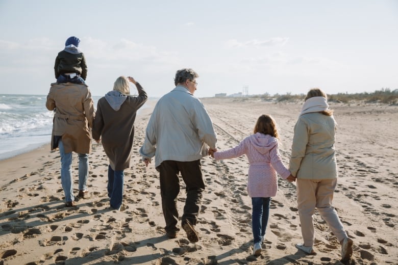 back view of big multigenerational family walking together on seashore