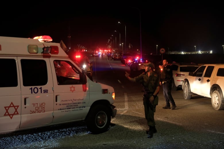 Emergency personnel direct an ambulance amid traffic