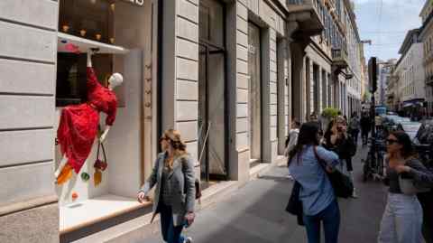 People walk outside the Hermès store on Via Monte Napoleone in Milan, Italy. The street is bustling with pedestrians and lined with luxury shops.