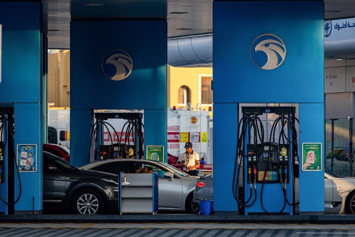 A worker refuels vehicles on the forecourt of an Adnoc gas station in the Jumeirah district of Duba