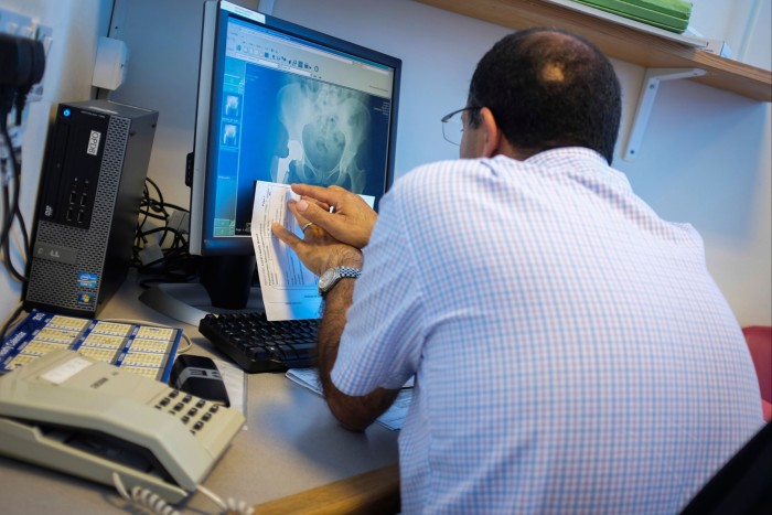 A consultant surgeon checking an x-ray after a hip replacement operation