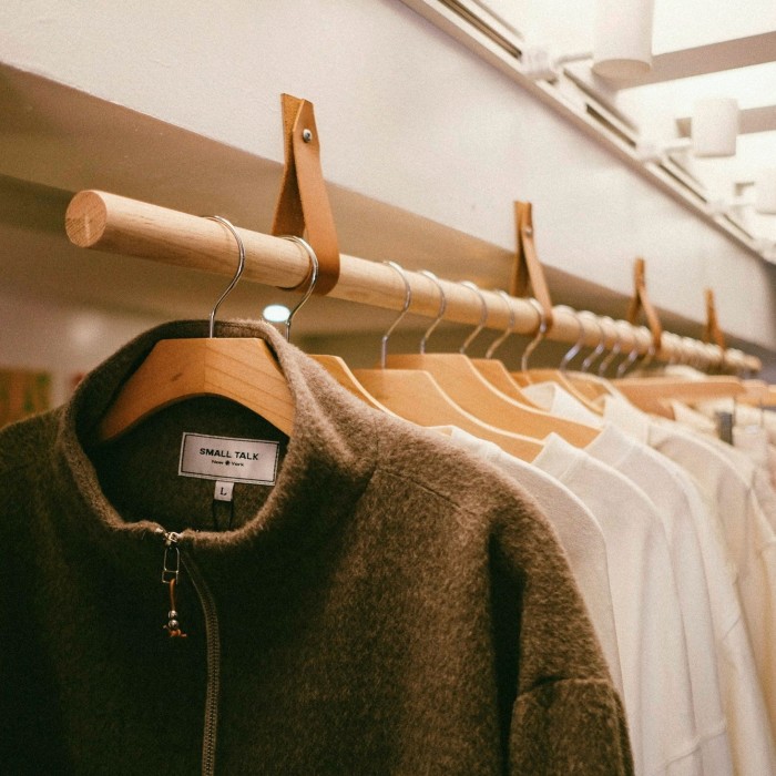 A jacket and some shirts hanging on a clothes rail in a men’s fashion store